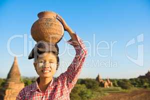 Asian traditional female farmer carrying clay pot on head