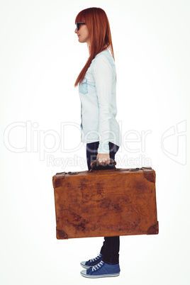 Side view of a smiling hipster woman holding suitcase