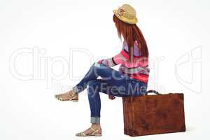 Hipster woman sitting on her suitcase