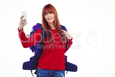 Smiling hipster woman with a travel bag taking selfie