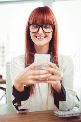 Smiling hipster businesswoman texting on her smartphone Smiling hipster businesswoman texting on her smartphone