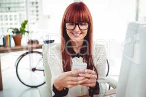 Smiling hipster businesswoman texting on her smartphone