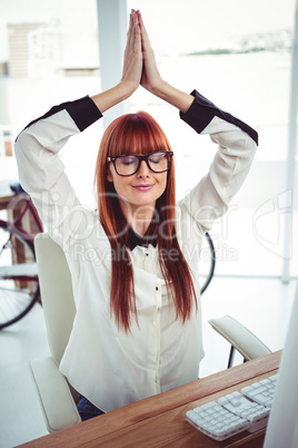 Hipster businesswoman meditating with hands raised