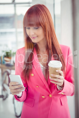 Hipster businesswoman holding coffee cup and smartphone