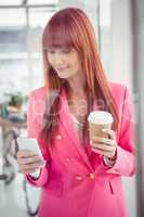 Hipster businesswoman holding coffee cup and smartphone