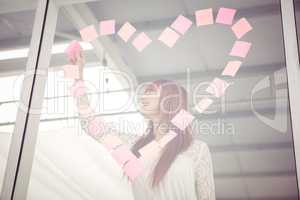 Smiling hipster woman doing a heart in post-it