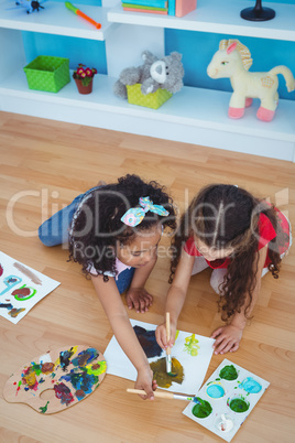 Cute girls painting laying on the floor