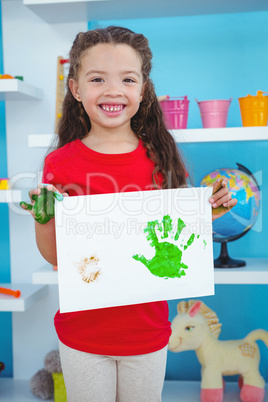 Cute girl showing paper with colored hands prints on it