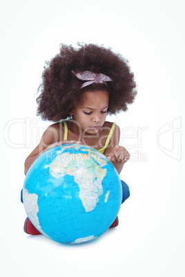 Cute girl sitting on floor looking at globe