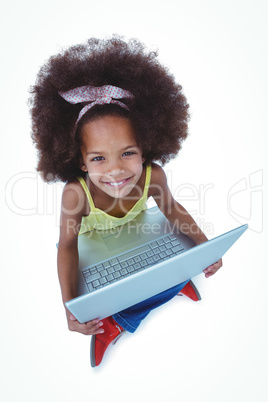 Cute girl sitting on floor using laptop and smiling at camera