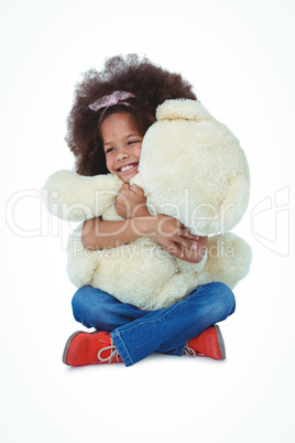 Cute girl sitting on the floor hugging teddy bear