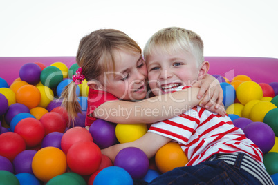 Cute smiling kids in sponge ball pool hugging
