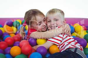 Cute smiling kids in sponge ball pool hugging