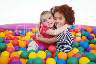 Cute smiling girls in sponge ball pool hugging