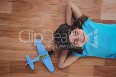 Smiling girl laying on the floor wearing aviator glasses and hat