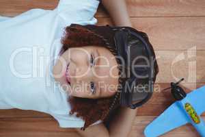 Smiling girl laying on the floor wearing aviator glasses and hat