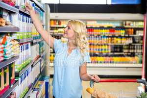 Smiling woman taking food from shelf