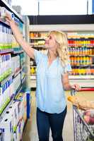 Smiling woman taking food from shelf