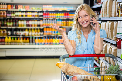 Smiling woman with cart using smartphone