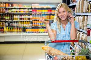 Smiling woman with cart using smartphone