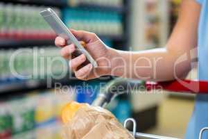 Woman with cart using smartphone