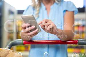 Woman with cart using smartphone