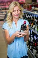 Beautiful woman looking wine bottle