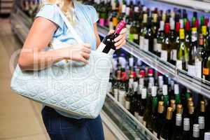 Woman putting wine bottle in bag