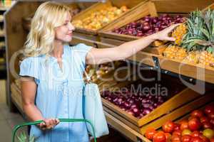 Blonde woman with basket taking pineapple