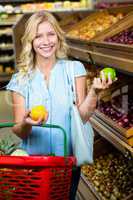 Smiling woman with shopping basket holding apples