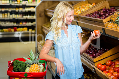 Blonde woman holding and looking tomato