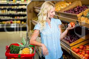 Blonde woman holding and looking tomato