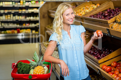 Smiling blonde woman holding tomato