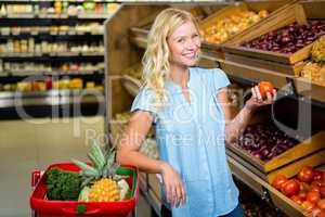 Smiling blonde woman holding tomato