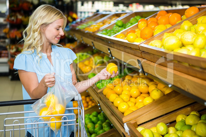 Smiling woman putting oranges in plastic bag