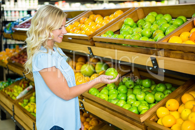 Smiling woman holding and looking an apple