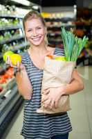 Beautiful woman standing with grocery bag and apples