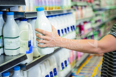 Womans hand holding milk bottle