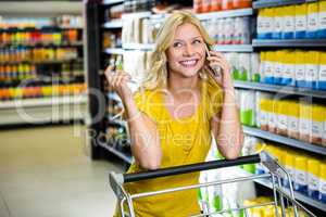 Pretty woman having phone call and pushing trolley