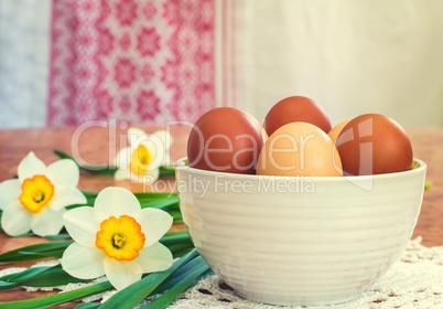 Easter eggs in a ceramic vase and flowers daffodils.