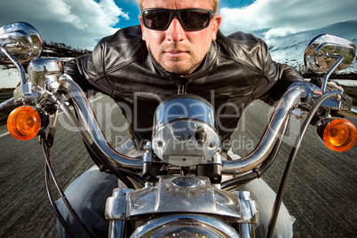 Funny Biker in sunglasses and leather jacket racing on mountain