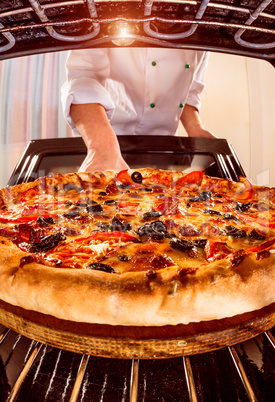 Chef cooking pizza in the oven.