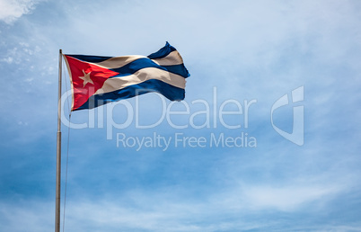 Cuban flag flying in the wind on a backdrop of blue sky.
