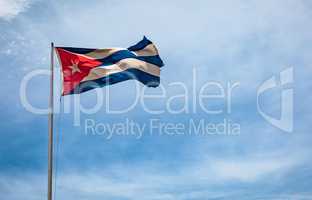 Cuban flag flying in the wind on a backdrop of blue sky.