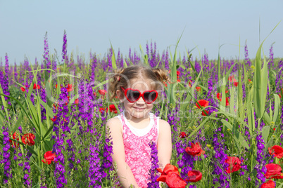 little girl standing in meadow with colorful flowers