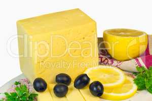 Big piece of cheese, lemon and olives on a white background.