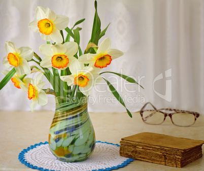 Blossoming narcissuses in a vase on a table.
