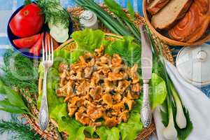 Fried mushrooms of chanterelle on a dish together with lettuce l