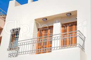 Fragment of a facade of a house with a balcony and blinds from t