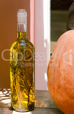 Still life: a bottle of olive oil , along with herbs, and pumpki